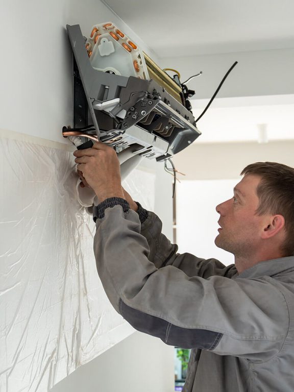 An air conditioning tech installs a mini split wall unit.